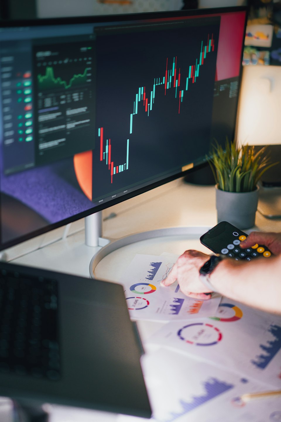 Persoon analyseert financiële gegevensgrafieken op een wit bureau.