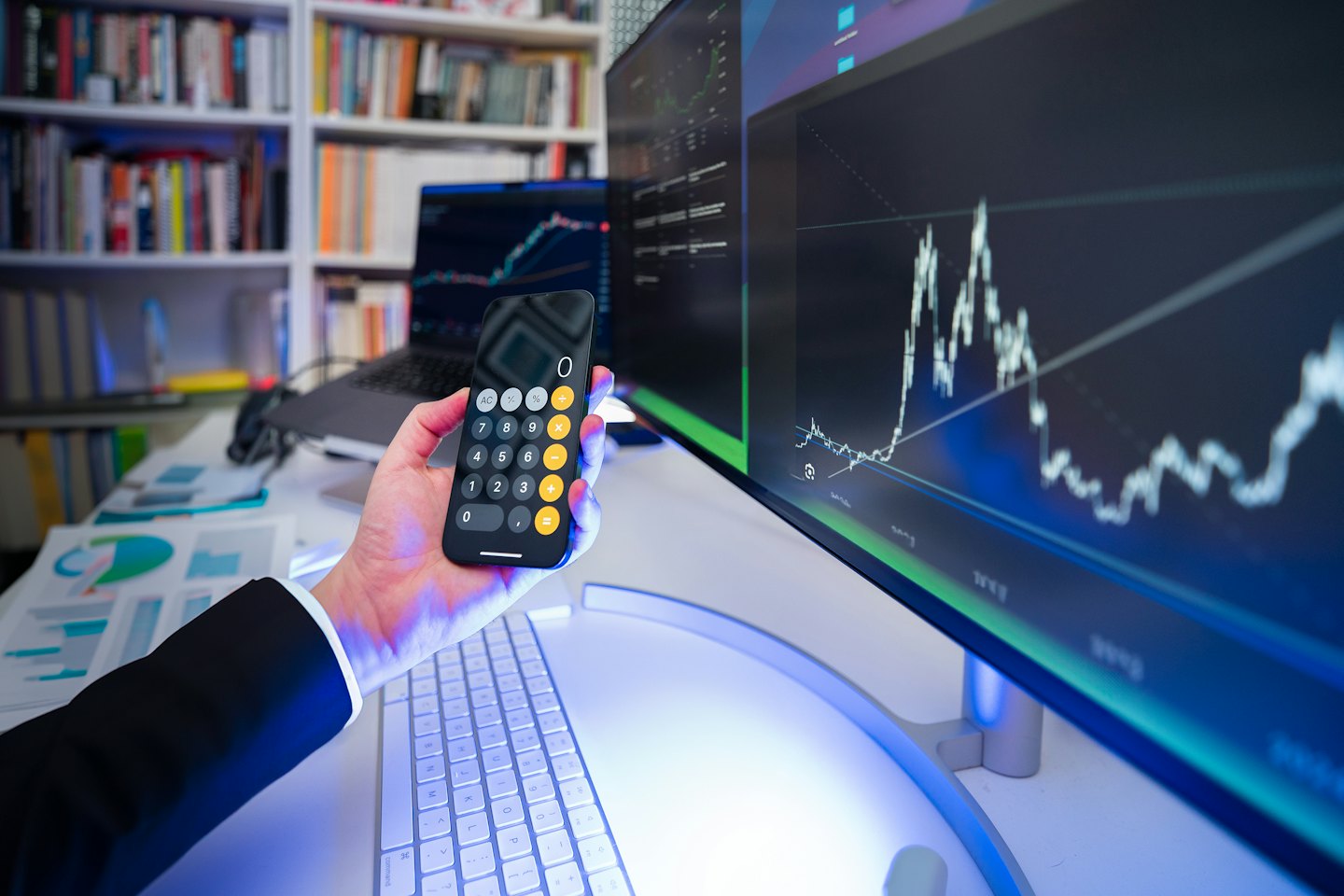 Persoon analyseert financiën met smartphone en computer.